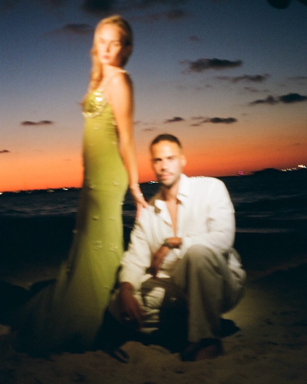 Couple on the beach under an orange sunset sky