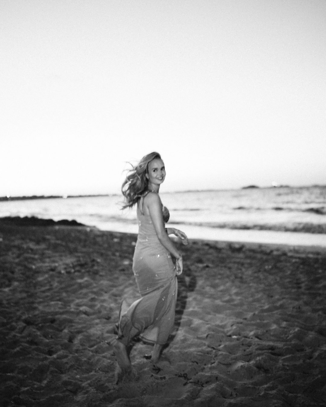 Woman in a long gown walking on the beach, black and white