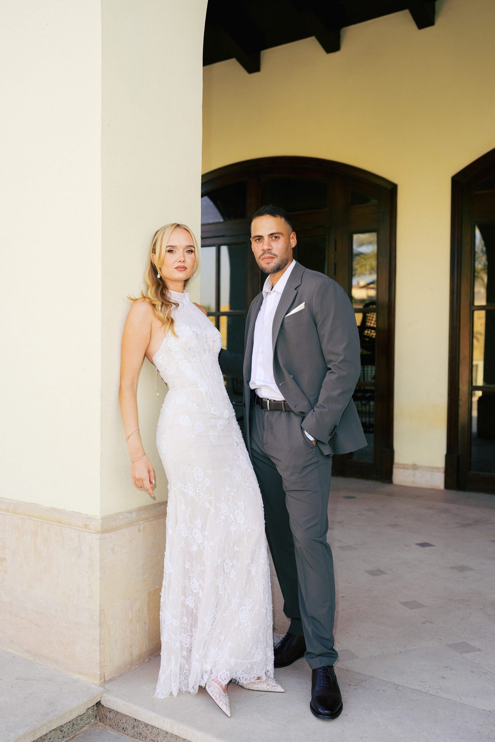 Bride and groom standing together under a covered arcade