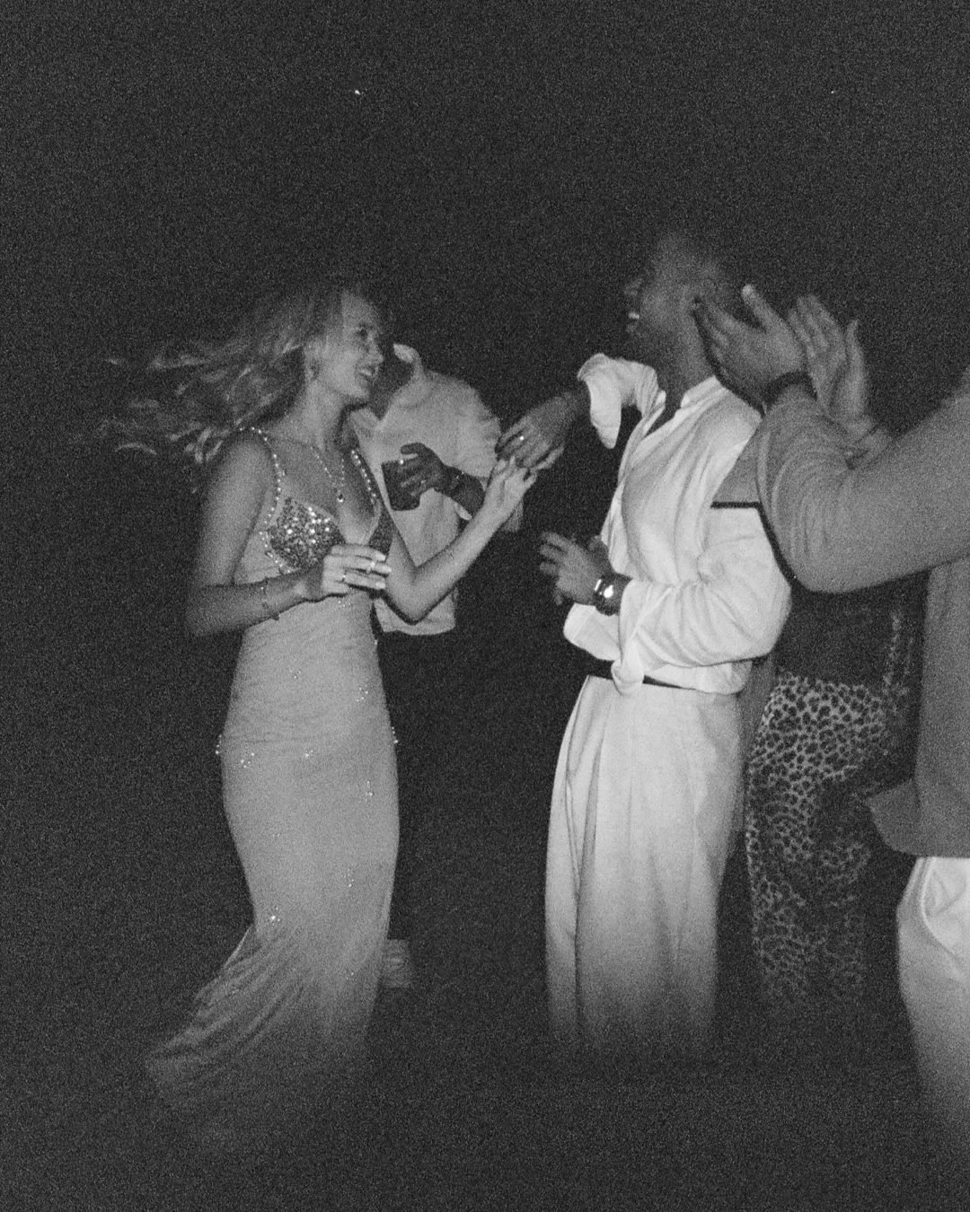 Guests dancing at night in grainy light, black and white