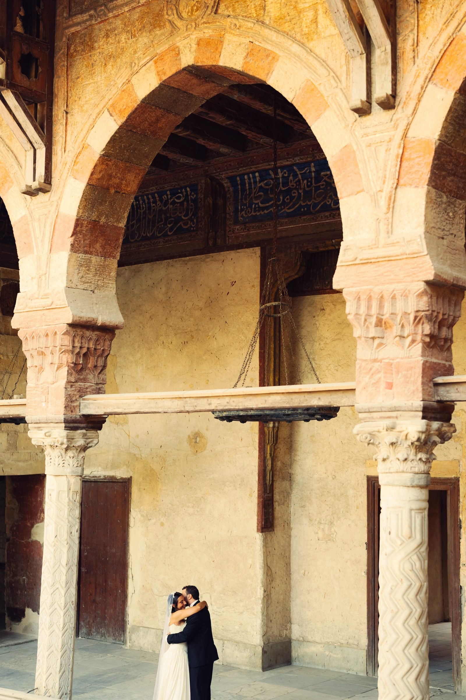 Couple embracing beneath carved stone arches