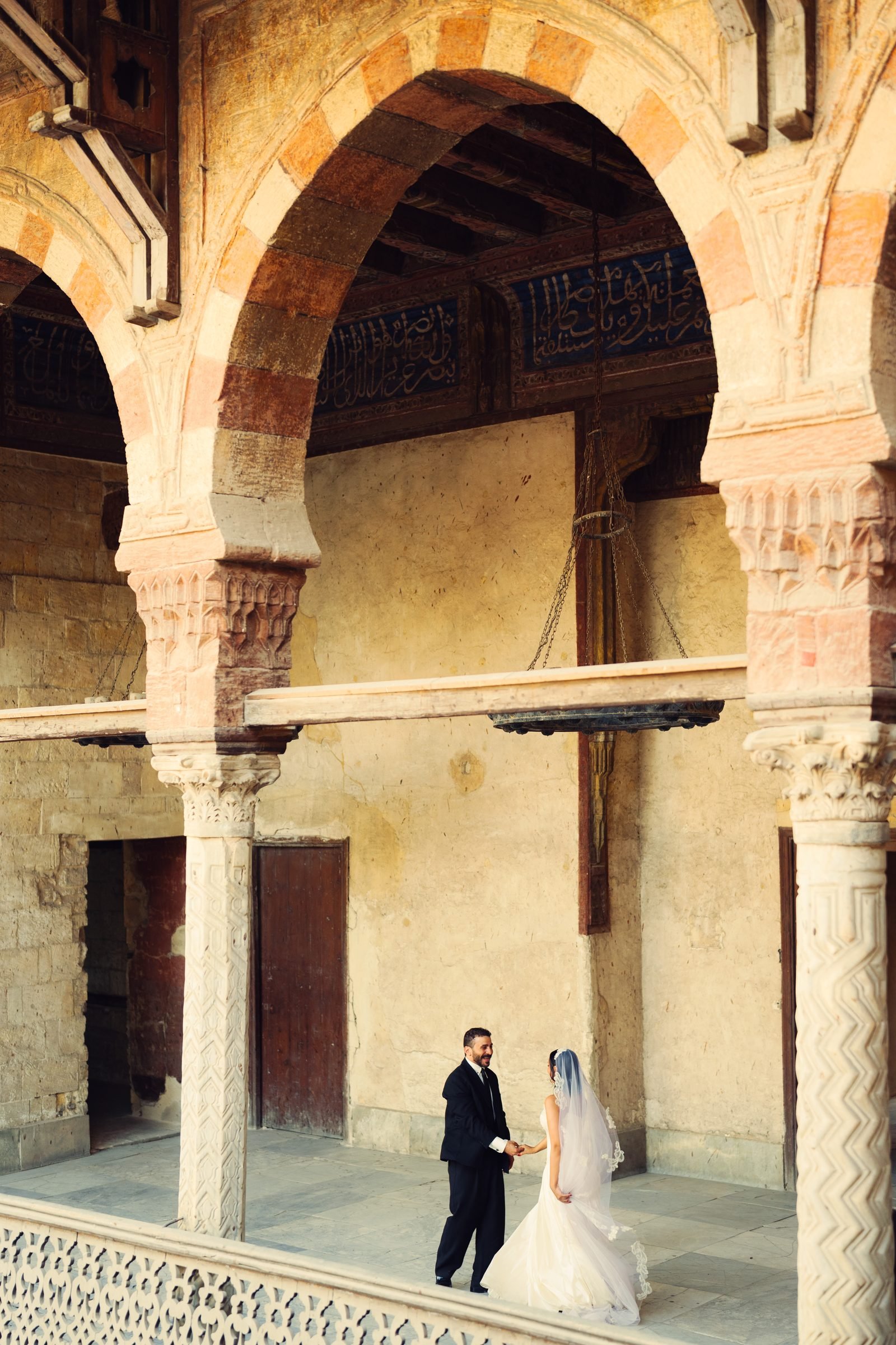 Bride and groom walking beneath stone arches