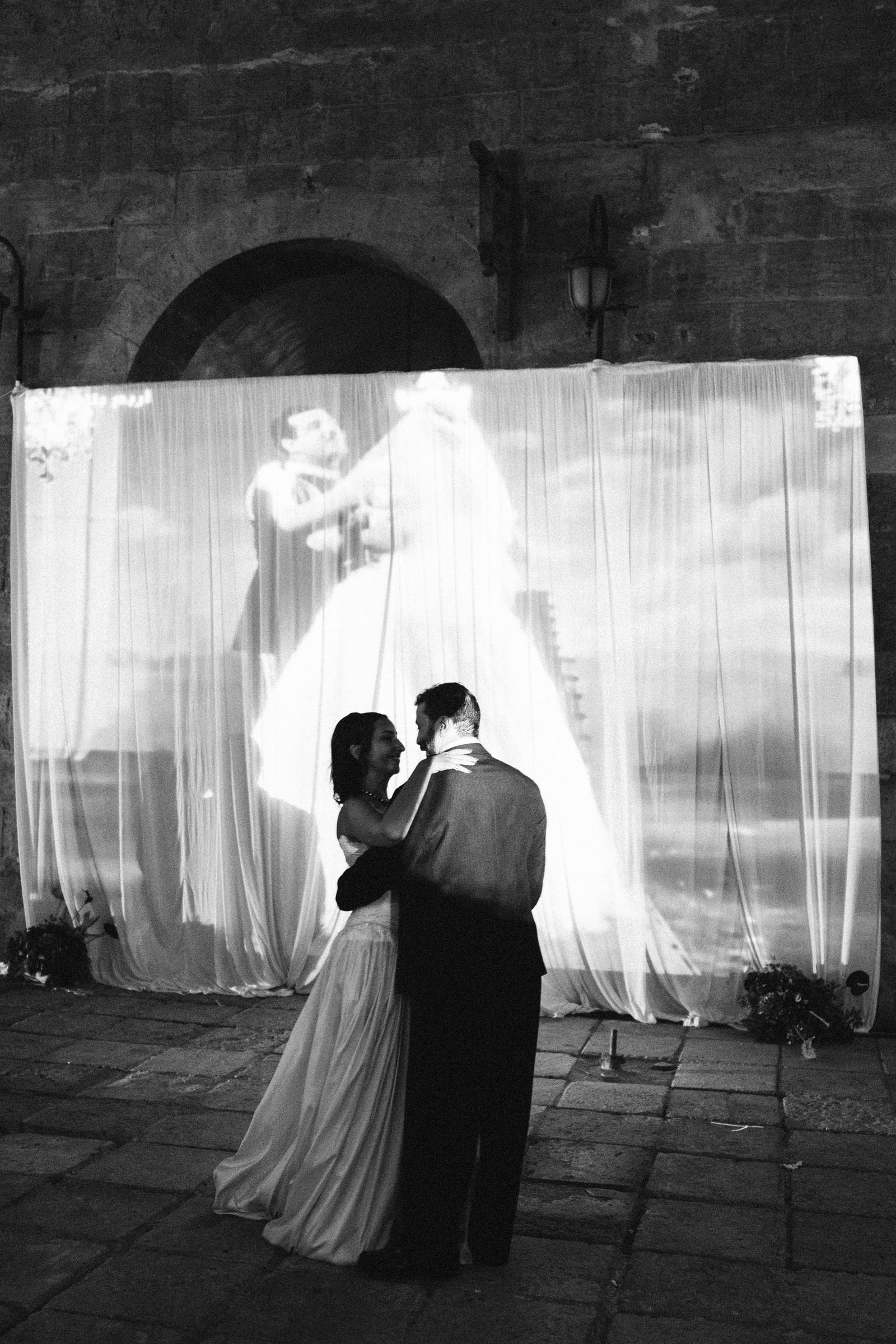 Couple dancing in front of a projected screen, black and white
