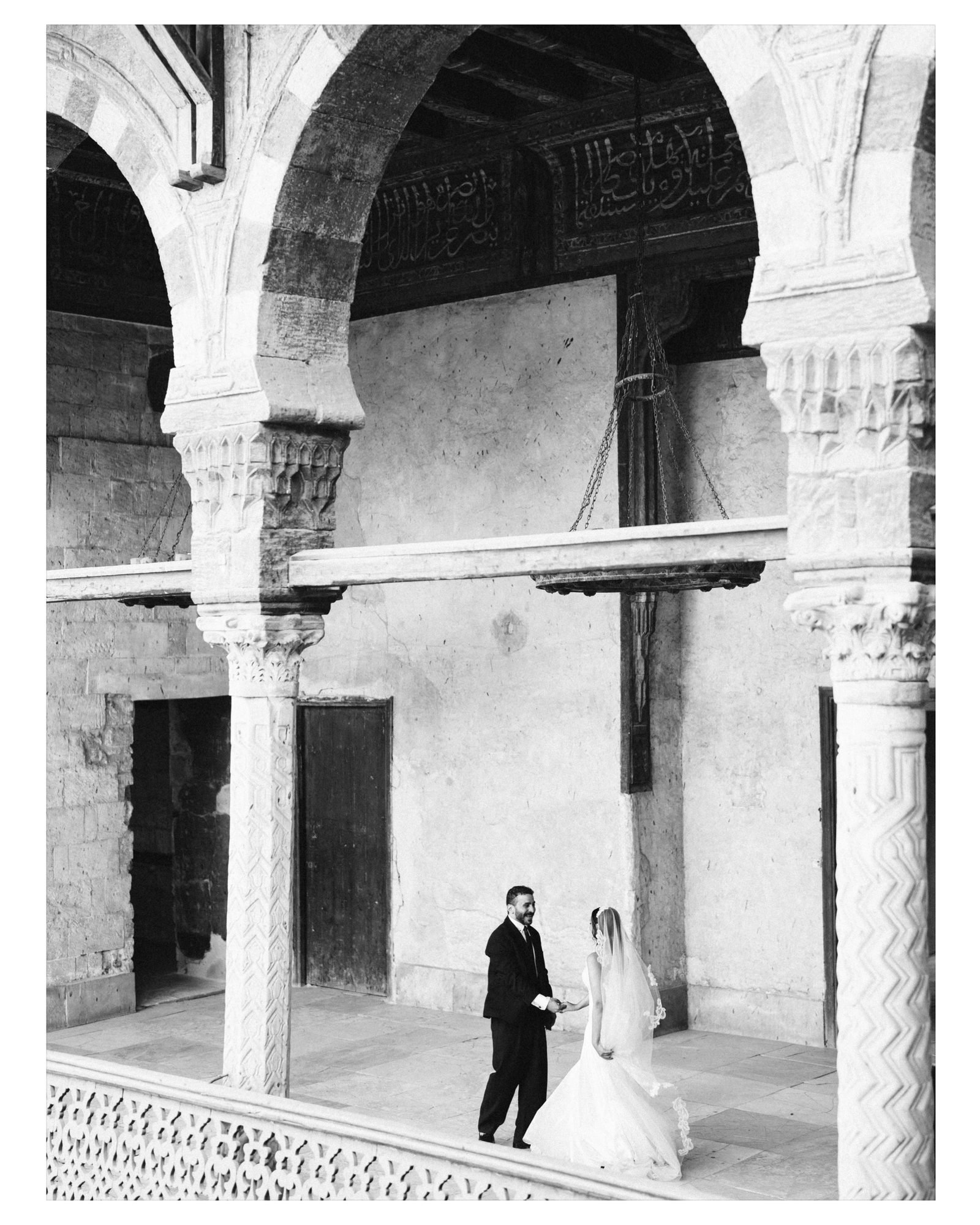 Couple standing between stone arches, black and white