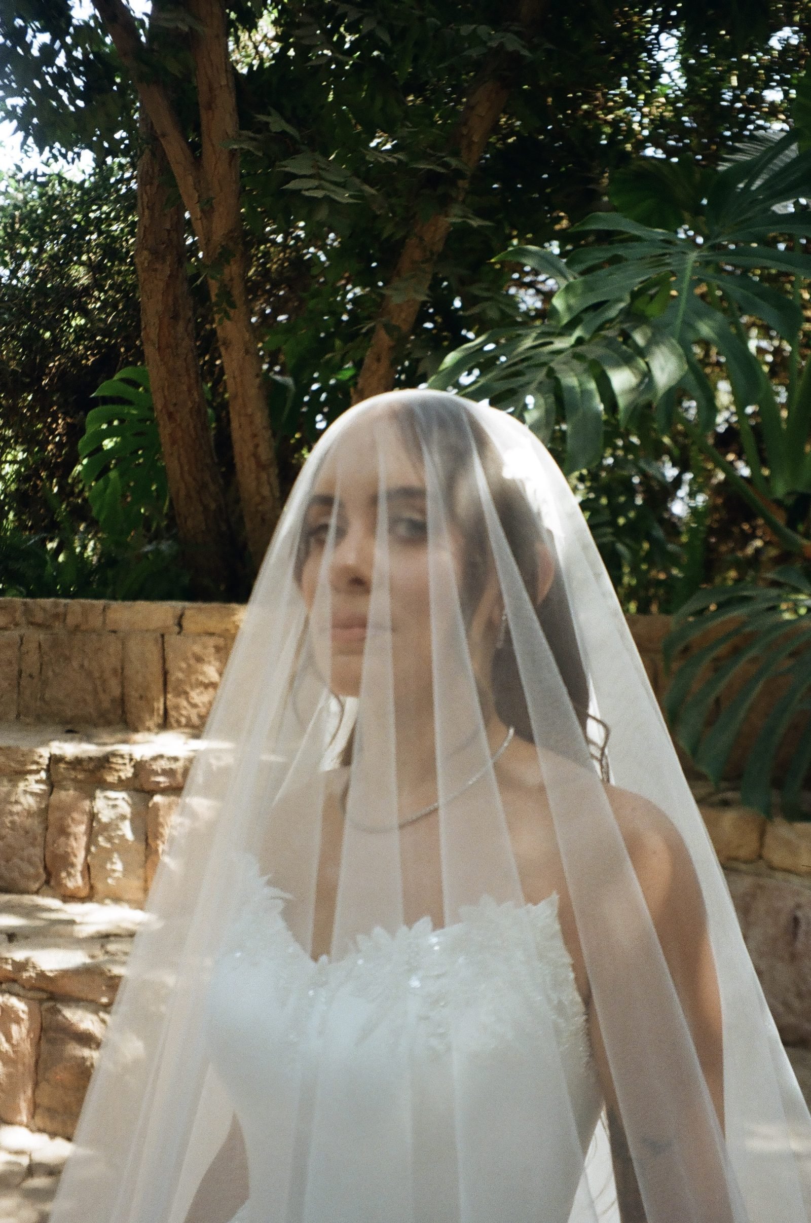 Bride in a veil among palm leaves