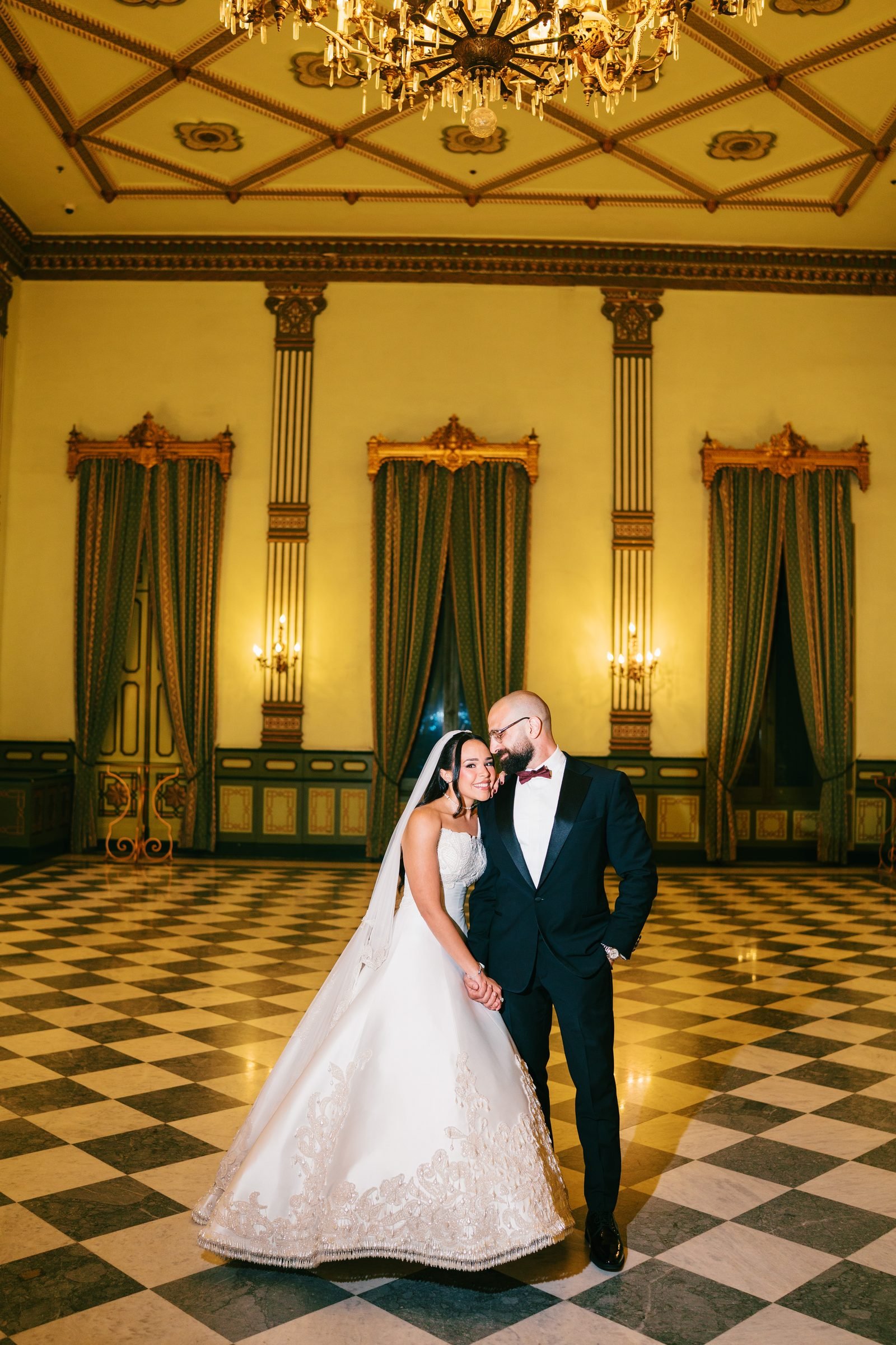 Bride and groom on a checkered floor in a grand hall