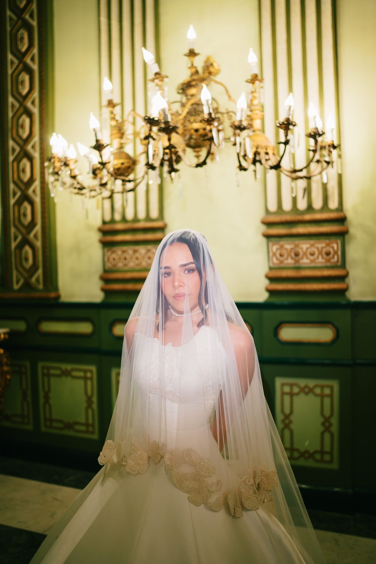 Bride in a veil beneath a chandelier