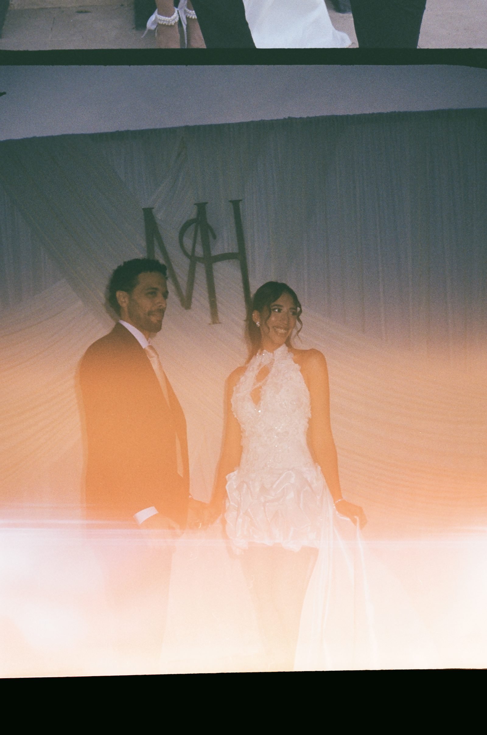Bride and groom behind a glowing monogram backdrop