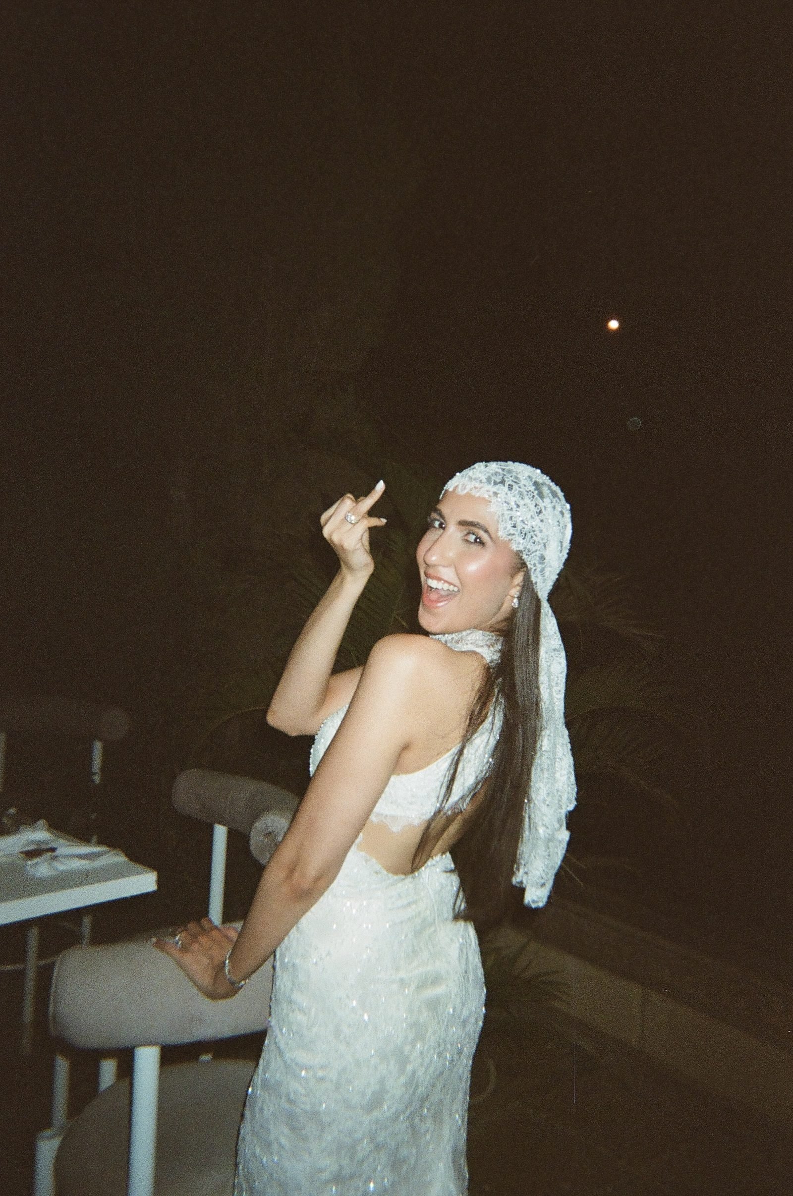 Bride in a headscarf turning to the camera at night