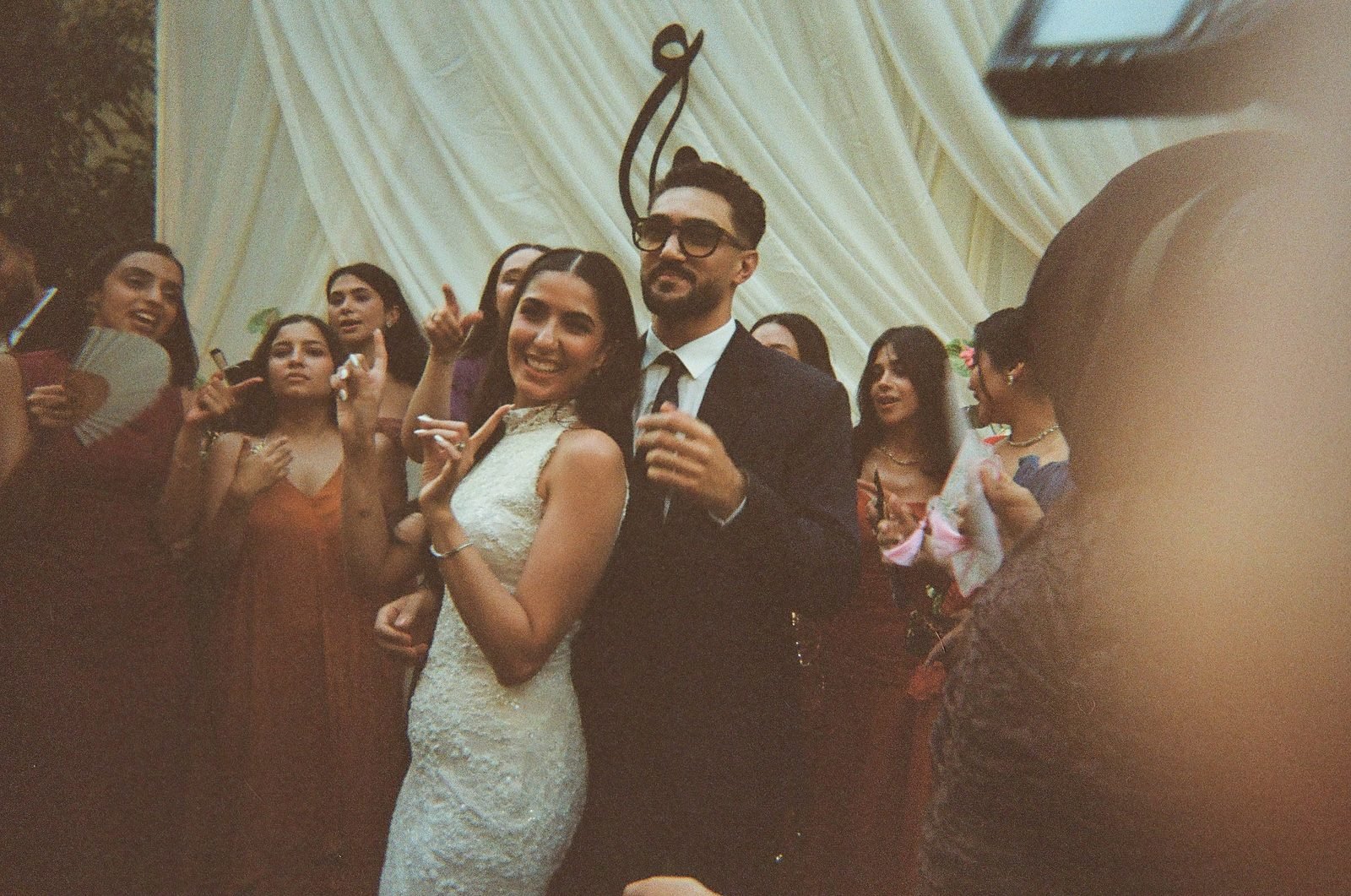Guests and the couple celebrating under a draped canopy