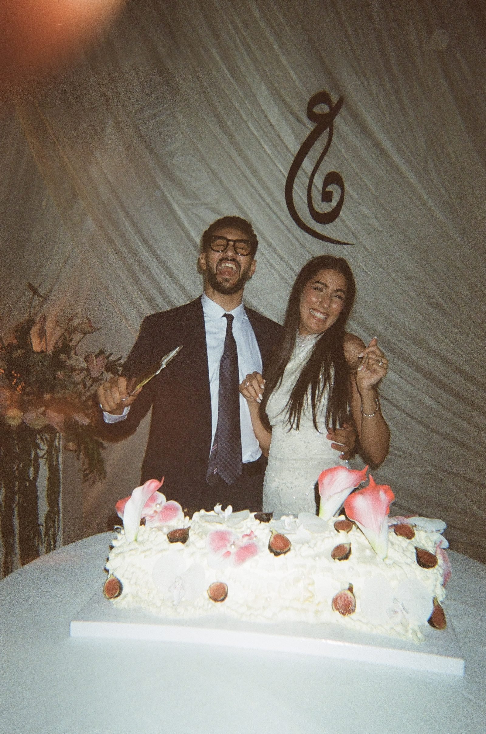 Couple standing behind their wedding cake