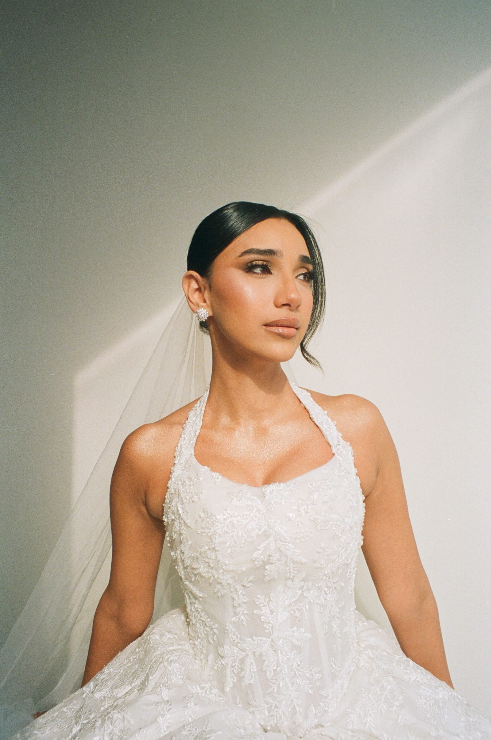 Bride in a halter gown and veil looking aside