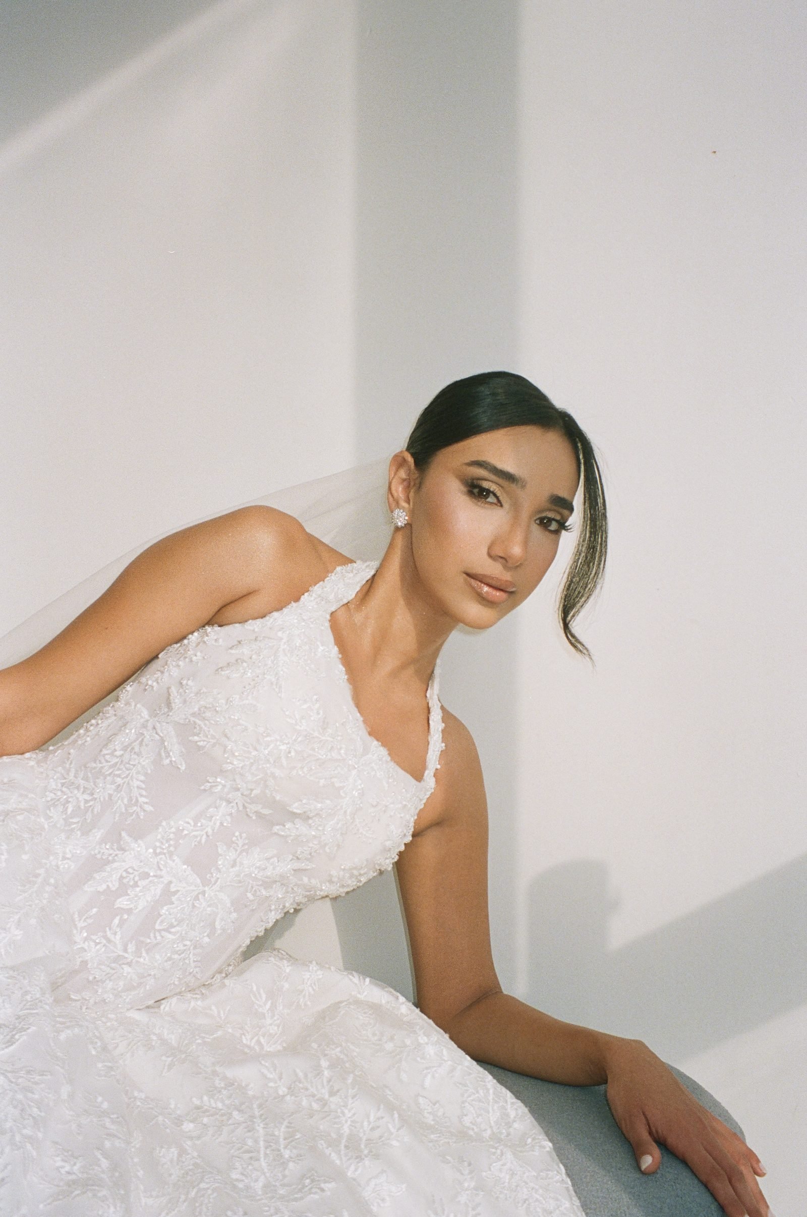 Bride in a lace gown seated and looking at the camera