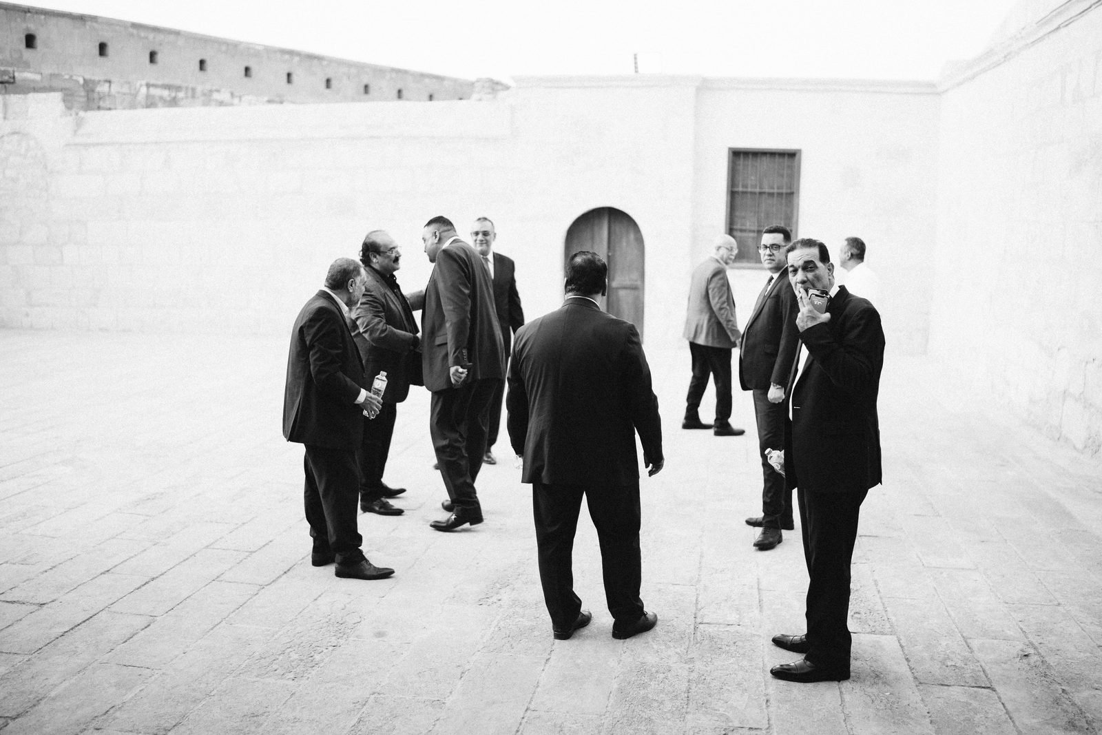 Groomsmen standing together in a courtyard, black and white