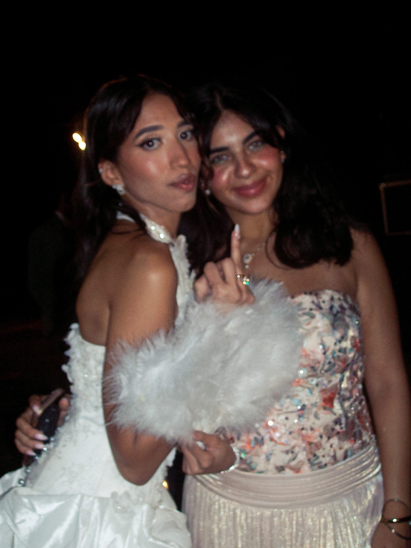 Bride and friend posing with a feather bouquet at night