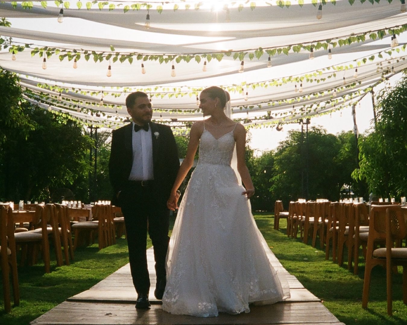 Couple walking beneath a vine-covered canopy