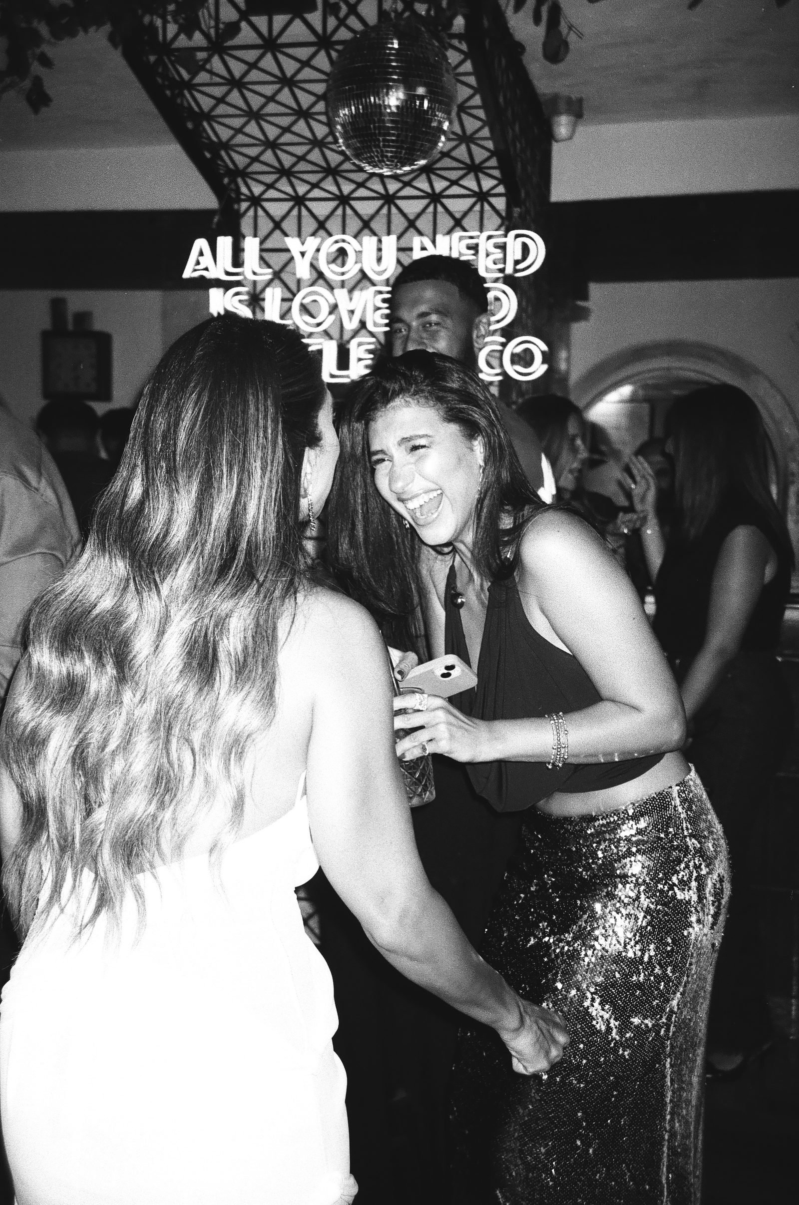 Friends laughing at the party under a neon sign, black and white