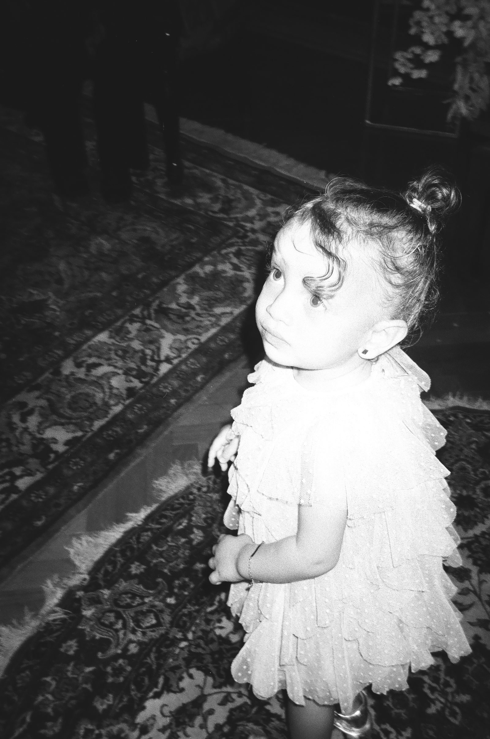 Little girl in a ruffled dress looking back, black and white