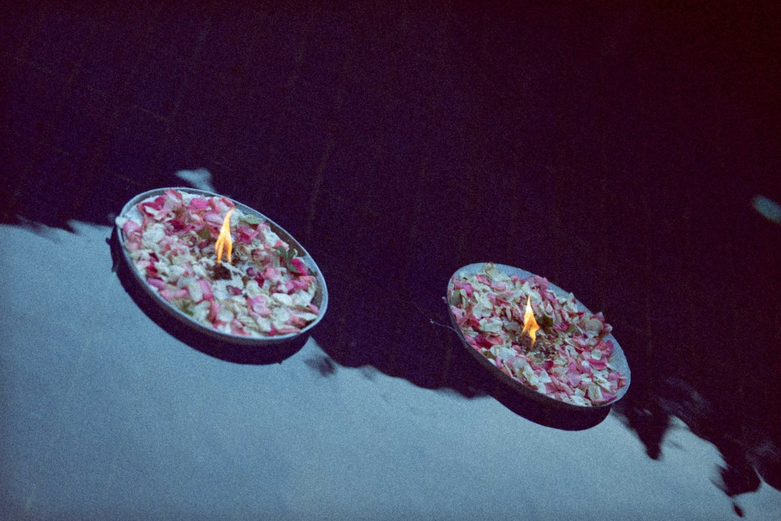 Floating candles and rose petals in shallow bowls of water