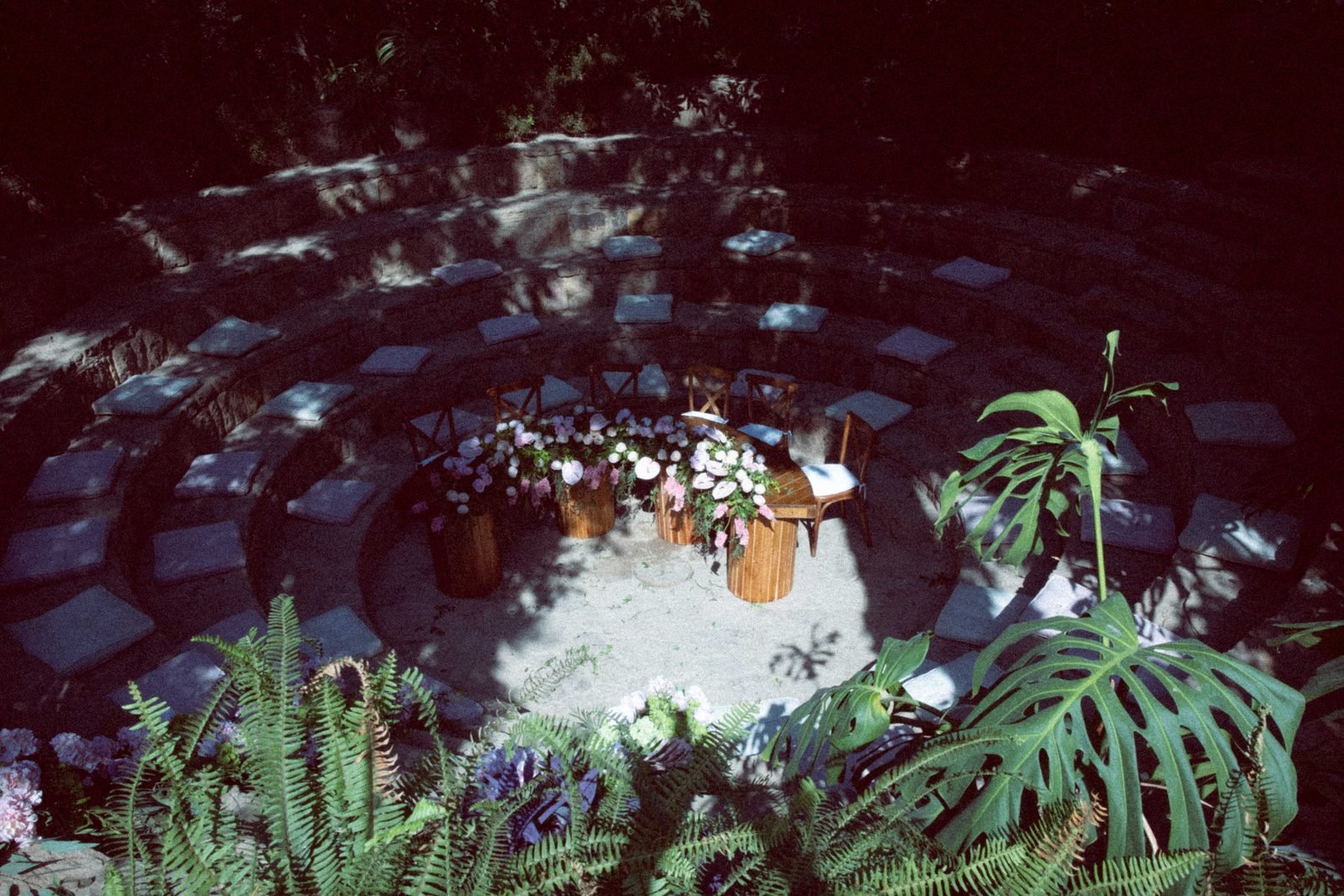 Circular stone seating area seen from above among ferns