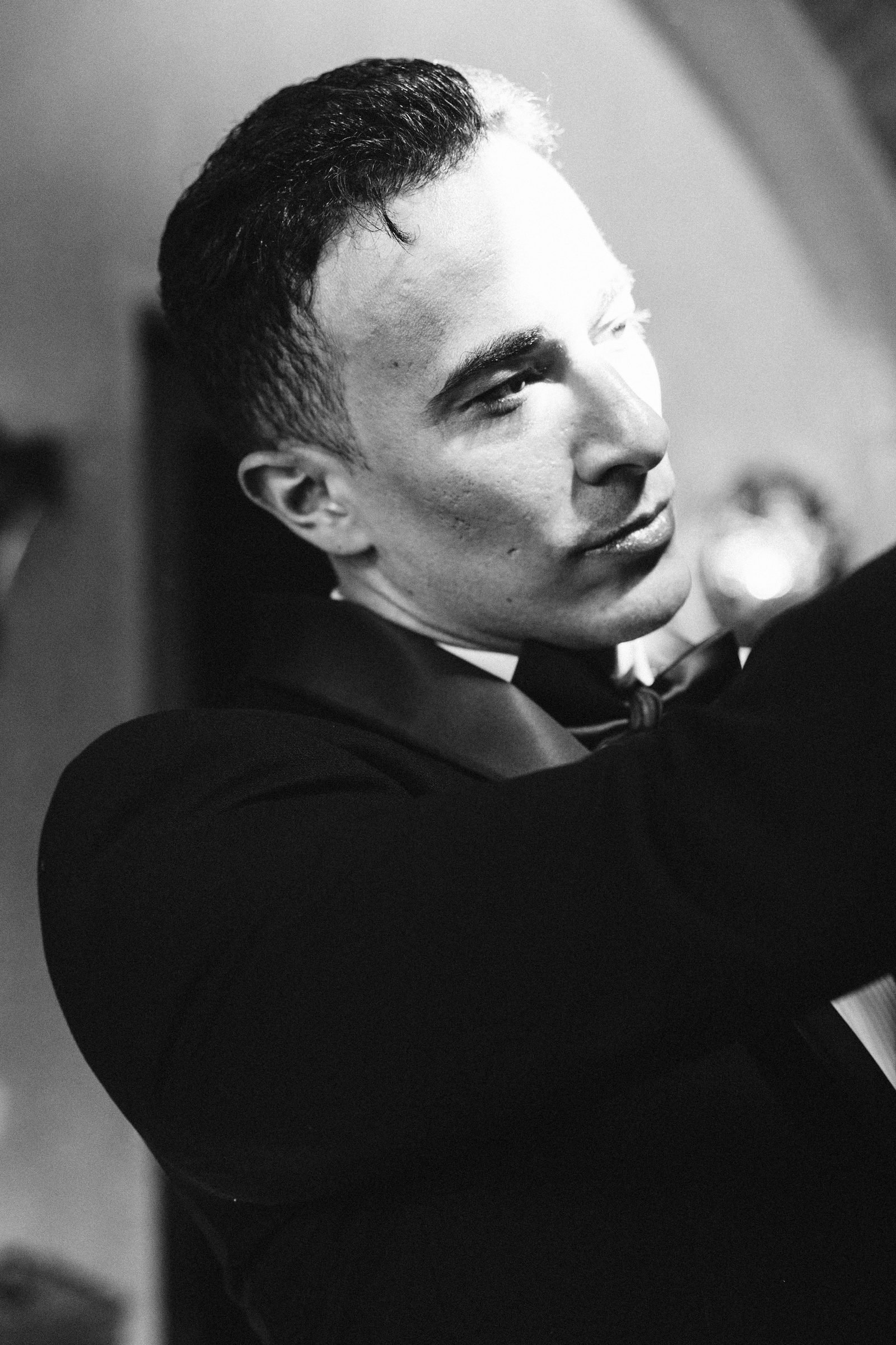 Groom in a tuxedo glancing aside, black and white