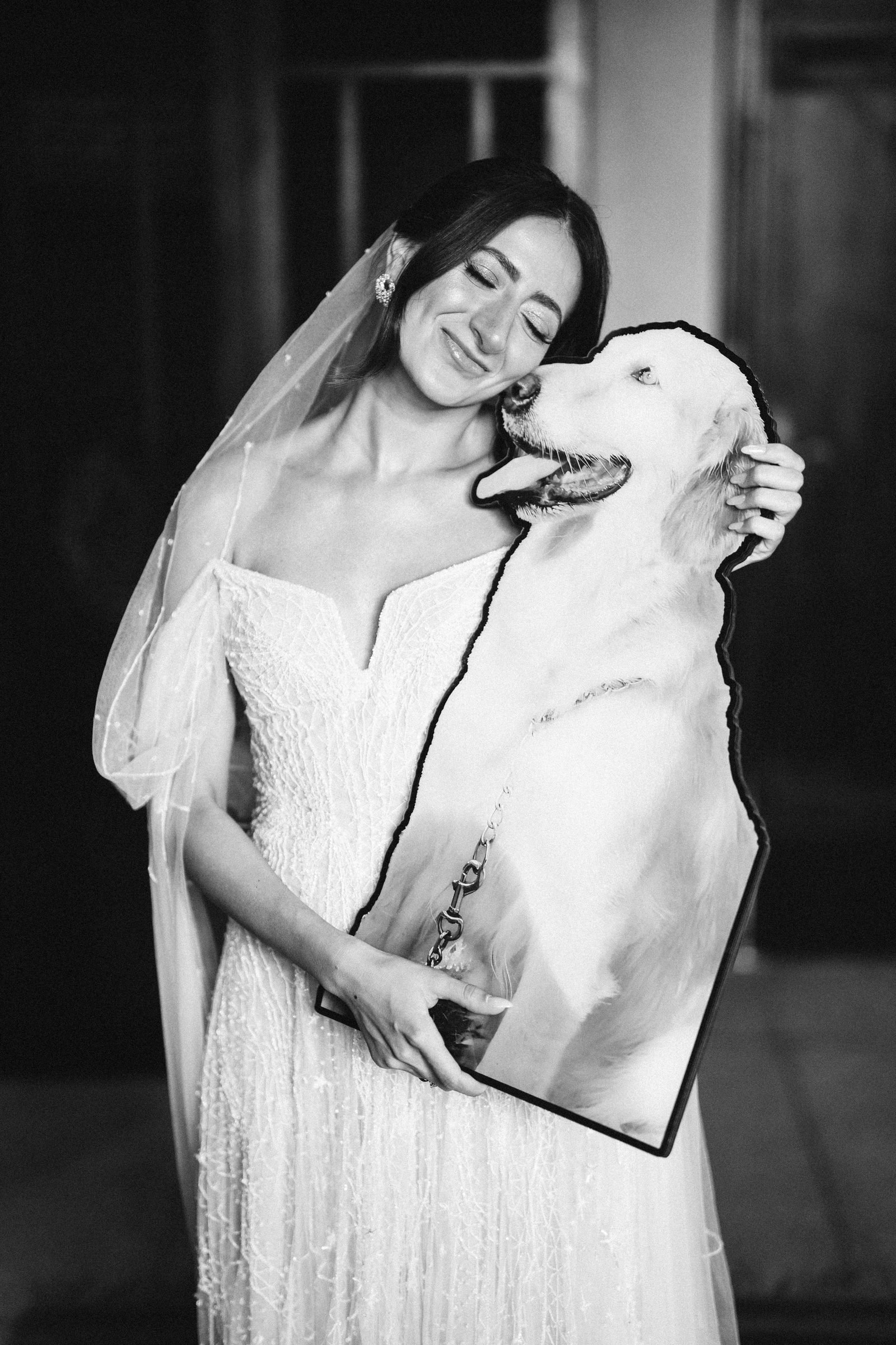 Bride in a veil holding a cut-out of a dog, black and white